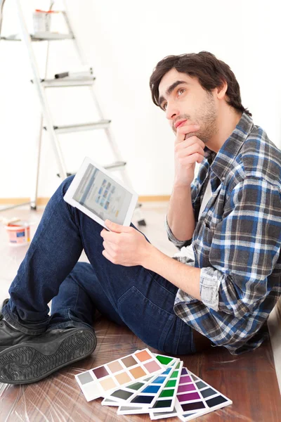 Mladý muž pomocí tablet při výběru barvy svého bytu — Stock fotografie