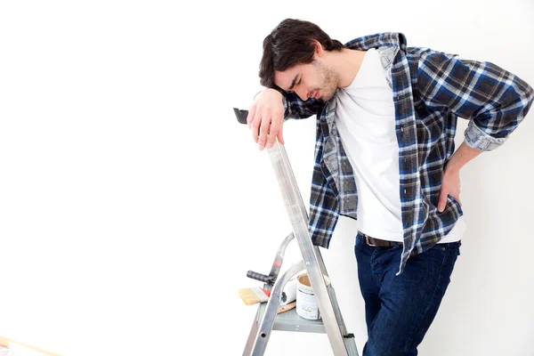 Jonge man lijden tijdens het werken aan een trapladder — Stockfoto