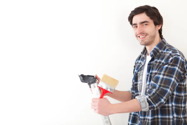 Jovem atraente pintando uma parede em seu novo apartamento — Fotografia de Stock