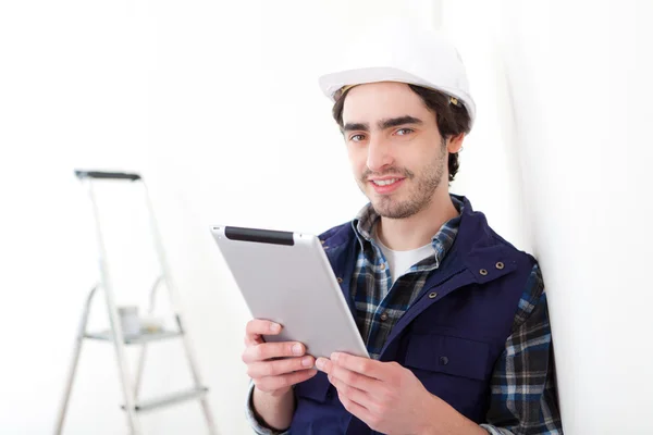 Hombre trabajador joven en un nuevo piso usando tableta —  Fotos de Stock