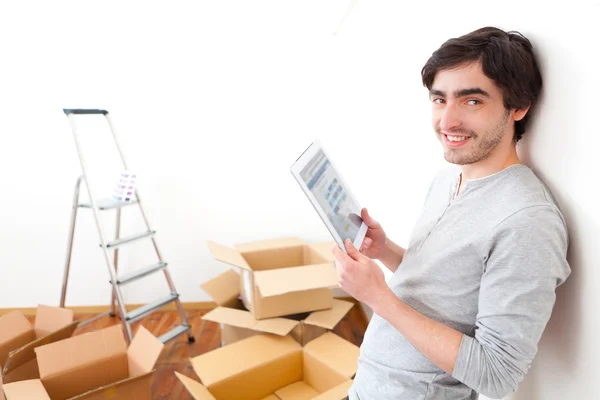 Knappe jonge man in zijn nieuwe appartement met behulp van Tablet PC — Stockfoto