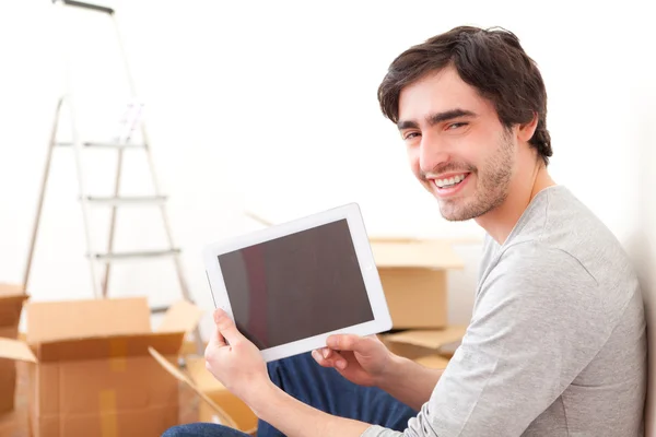 Knappe jonge man in zijn nieuwe appartement met behulp van Tablet PC — Stockfoto