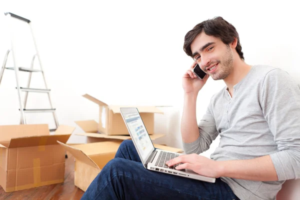 Schöner junger Mann in seiner neuen Wohnung bestellt auf seinem Laptop — Stockfoto