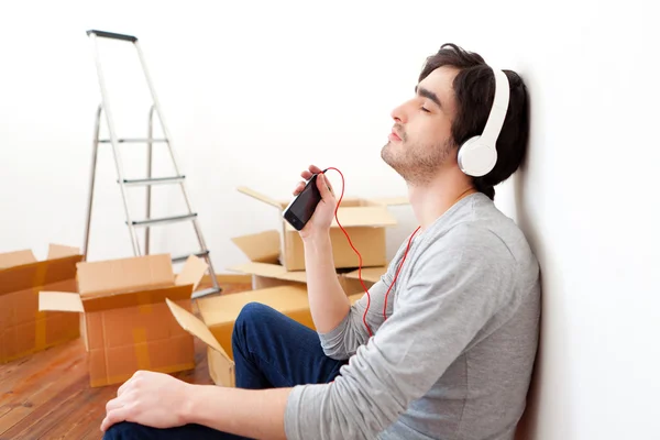 Young man listening music after moving in his new flat — Stock Photo, Image