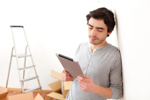 Knappe jonge man in zijn nieuwe appartement met behulp van Tablet PC — Stockfoto