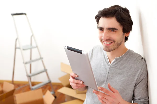 Schöner junger Mann in seiner neuen Wohnung mit Tablet — Stockfoto