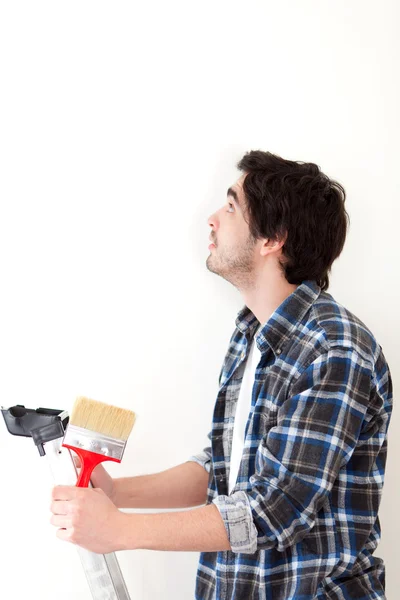 Attractive young man painting a wall in his new flat Stock Photo