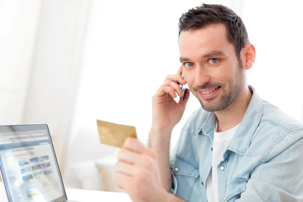 Jovem homem relaxado pagando online com seu cartão de crédito — Fotografia de Stock