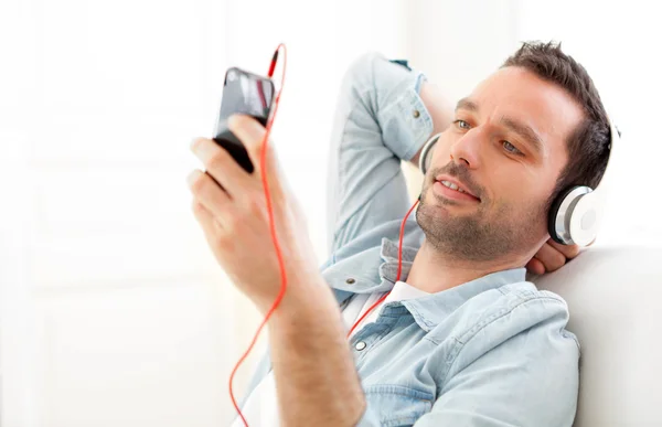 Ontspannen jongeman luisteren muziek in een bank — Stockfoto