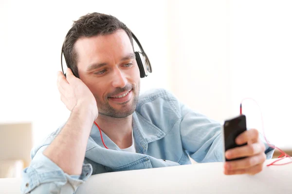 Молодой расслабленный мужчина слушает музыку на диване — стоковое фото