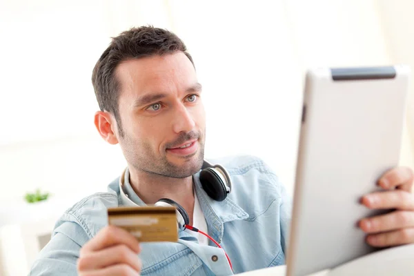 Young relaxed man buying music on tablet — Stock Photo, Image