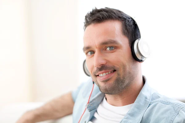 Ontspannen jongeman luisteren muziek in een bank — Stockfoto