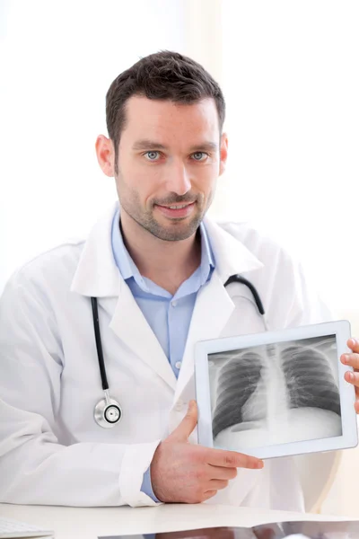 Médico joven mostrando radiografía en un comprimido —  Fotos de Stock