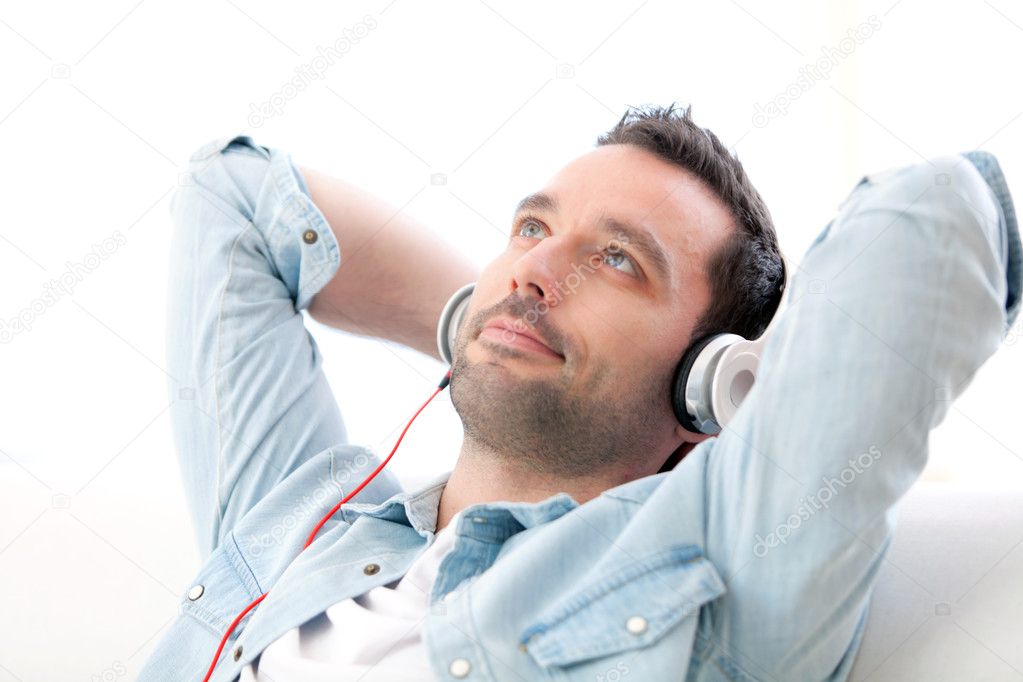 Young relaxed man listening music in a sofa