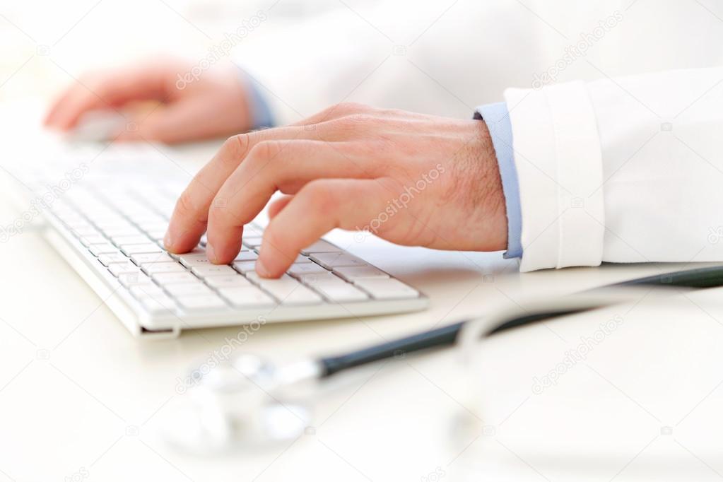 Details of doctor hands typing on keyboard