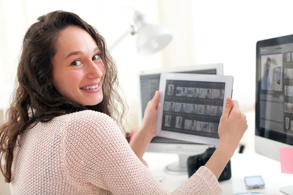 Young woman photographer choosing pictures on tablet — Stock Photo, Image