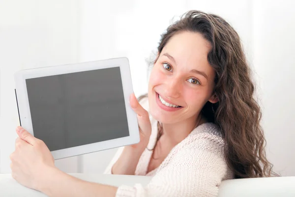 Portret van een jonge aantrekkelijke vrouw met behulp van Tablet PC op sofa — Stockfoto