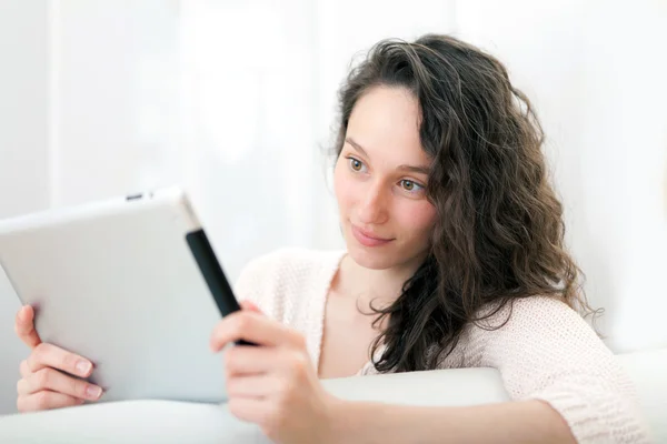 Portret van een jonge aantrekkelijke vrouw met behulp van Tablet PC op sofa — Stockfoto
