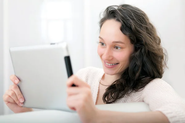 Portret van een jonge aantrekkelijke vrouw met behulp van Tablet PC op sofa — Stockfoto