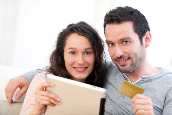 Молодая счастливая пара делает покупки на планшете — стоковое фото