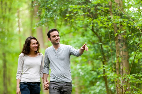 Pareja joven dando un paseo por un bosque — Foto de Stock