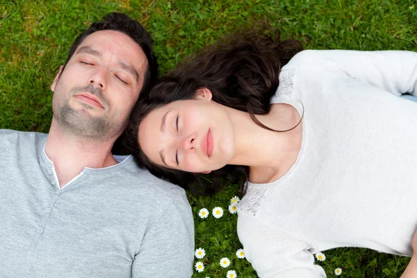 Attractive couple lying in grass at the park — Stock Photo, Image