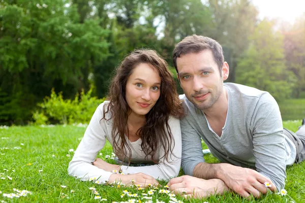 Atractiva pareja tumbado en la hierba en el parque — Stockfoto