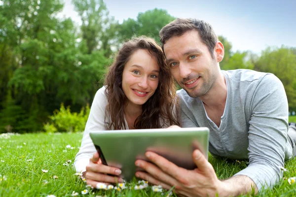 Jonge mooie paar met behulp van Tablet PC in het park — Stockfoto