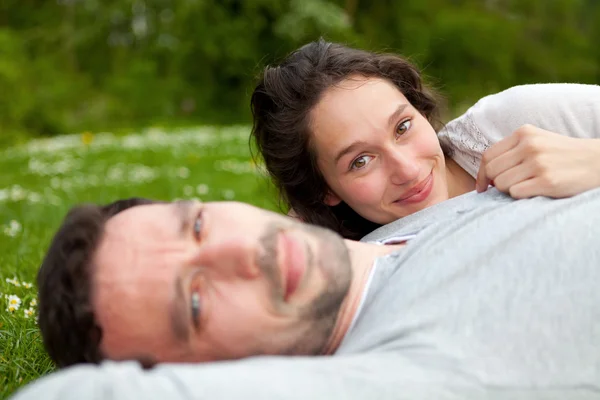 Attraktives Paar liegt im Gras am Park — Stockfoto