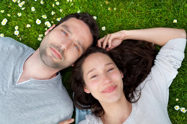 Attractive couple lying in grass at the park — Stock Photo, Image
