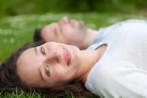 Atractiva pareja tumbada en el césped en el parque —  Fotos de Stock