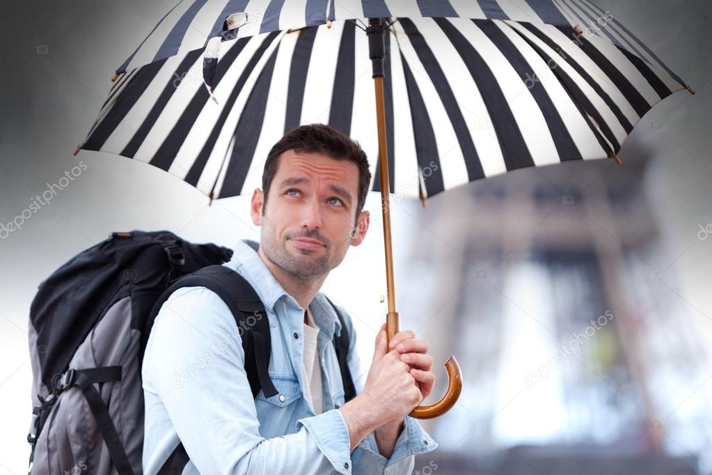 Young attractive man suffering rain in Paris
