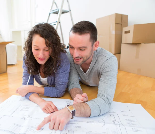 Junges Paar beobachtet Pläne in der neuen Wohnung — Stockfoto
