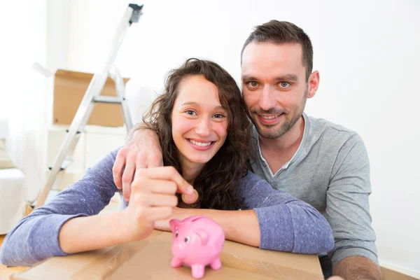 Casal jovem economizando dinheiro em um banco porquinho — Fotografia de Stock