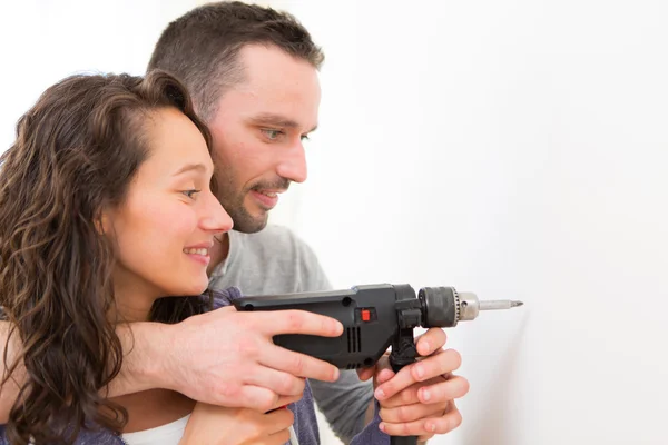 Hombre atractivo ayudando a su novia usando un taladro —  Fotos de Stock