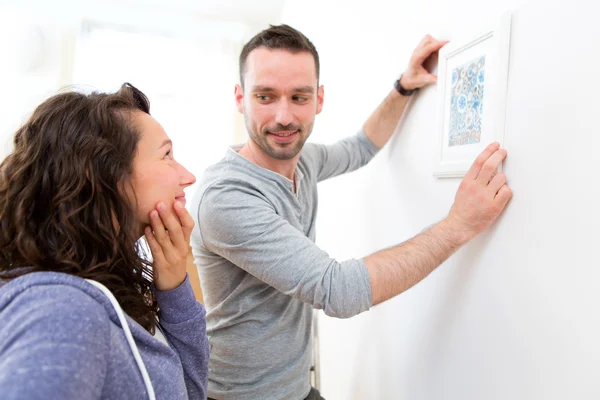 Couple accrocher une peinture dans leur nouvel appartement — Photo