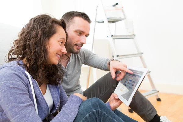 Young couple using tablet while moving in new flat — Stock Photo, Image