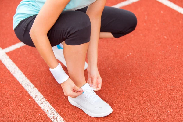 Vrouw stropdas omhoog haar schoenkant in het stadion — Stockfoto