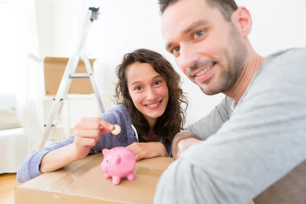 Casal jovem economizando dinheiro em um banco porquinho — Fotografia de Stock