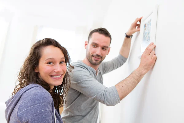 Couple accrocher une peinture dans leur nouvel appartement — Photo