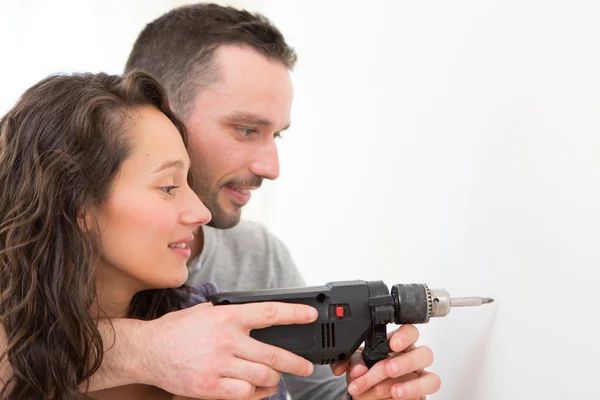 Hombre atractivo ayudando a su novia usando un taladro —  Fotos de Stock