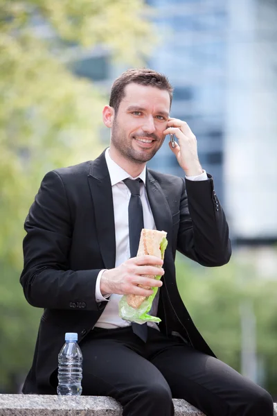 Businessman eating sandwich for lunch break — Stock Photo, Image