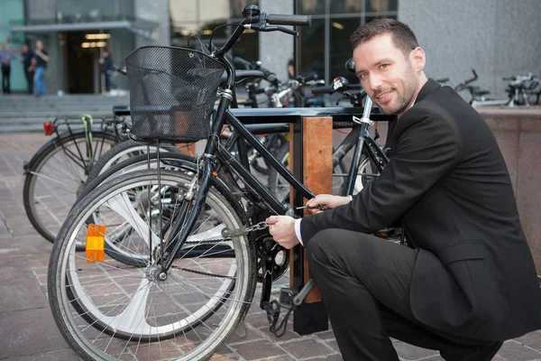 ビジネスマンの仕事の一日の後の彼の自転車ロックを解除します。 — ストック写真