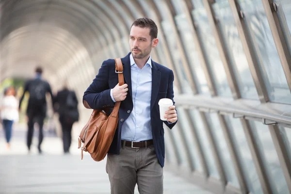 Young attractive man drinking coffee on his way — Stock Photo, Image