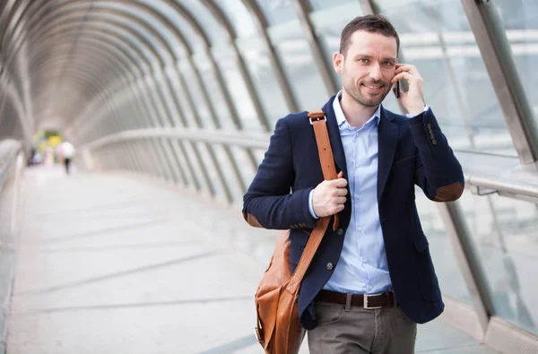 Young attractive man having a call in a airport hall — Stock Photo, Image