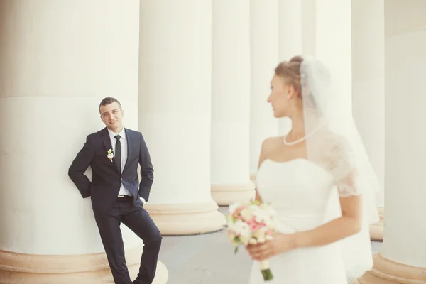 Mariée et marié posant près des colonnes blanches — Photo