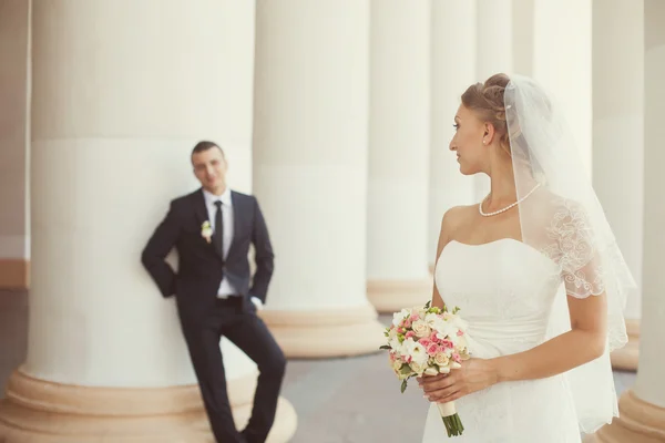 Sposo e sposo in posa vicino alle colonne bianche — Foto Stock