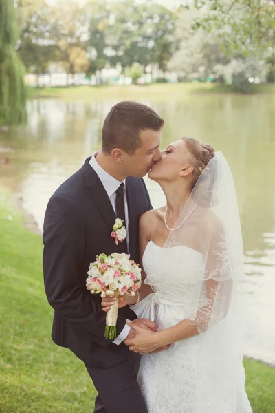 Bruid en bruidegom in park in de buurt van het meer — Stockfoto