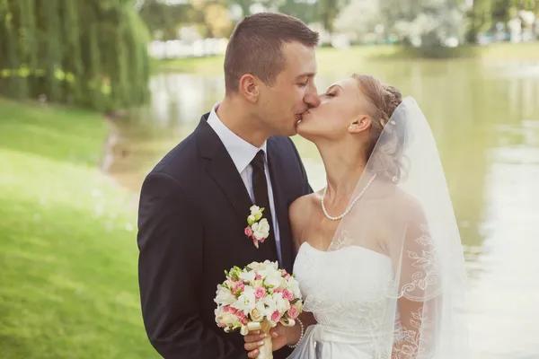 Nevěsta a ženich v parku u jezera — Stock fotografie