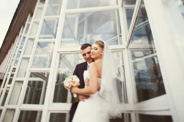 Novia y novio posando cerca del edificio de vidrio — Foto de Stock